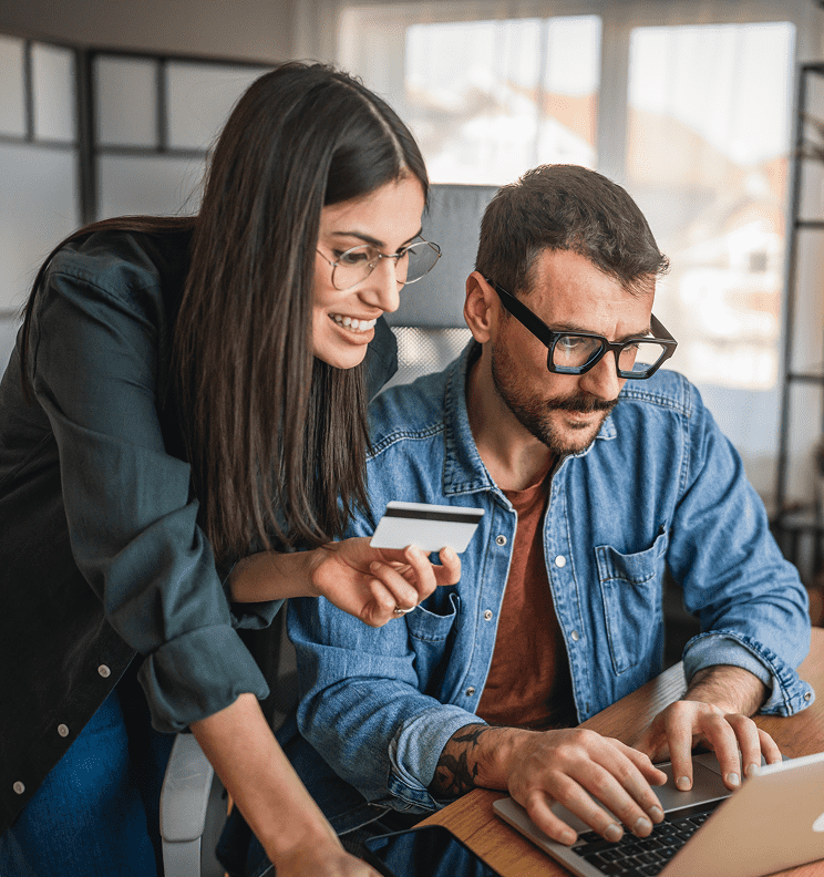 Two people collaborating on a laptop with a credit card